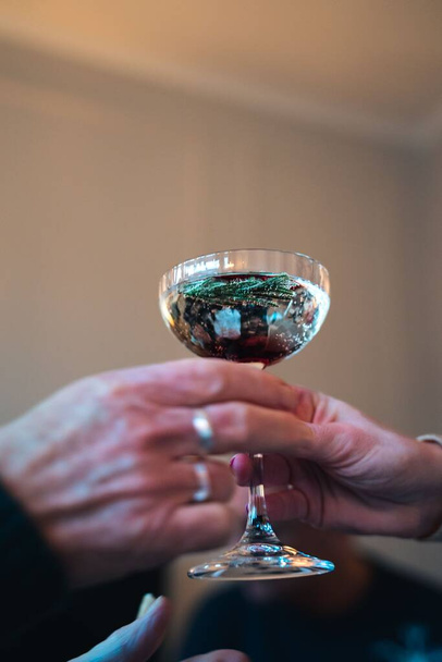 A vertical closeup of a glass of mulled wine being passed from hand to hand - Foto, Imagem
