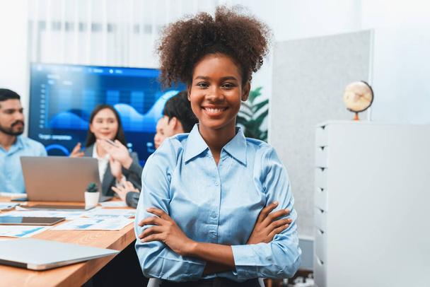 Bir grup ofis çalışanı ile birlikte arka planda ekranda gösterim paneliyle buluşan mutlu Afrikalı genç bir iş kadını portresi. Takım toplantısında kendine güveni tam bir ofis hanımı. Uyum - Fotoğraf, Görsel