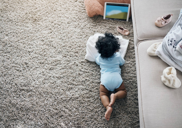 Ο καθένας χρειάζεται χρόνο για τον εαυτό του, ακόμη και τα μωρά. Στιγμιότυπο υψηλής γωνίας ενός αγνώριστου μωρού ξαπλωμένου στο πάτωμα του σαλονιού και βλέποντας ένα βίντεο σε ένα ψηφιακό tablet - Φωτογραφία, εικόνα