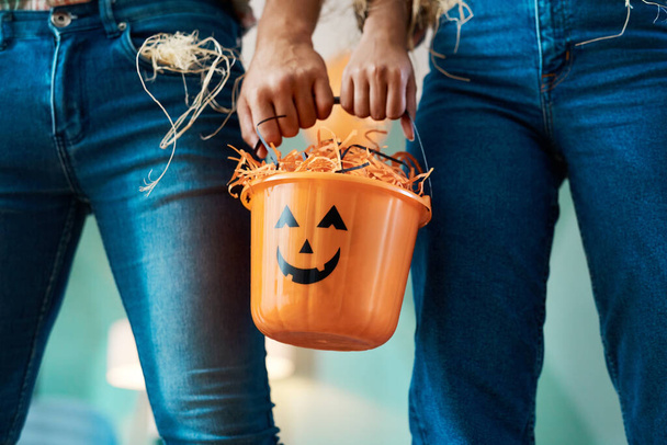 Trick-or-treating together means we get more candy. two unrecognizable people holding a bucket at home - Fotografie, Obrázek