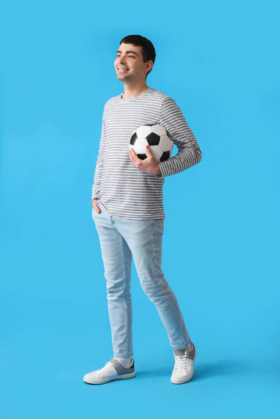 Young man with soccer ball on blue background - 写真・画像