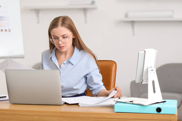 Female accountant working with laptop at table in office - Foto, imagen