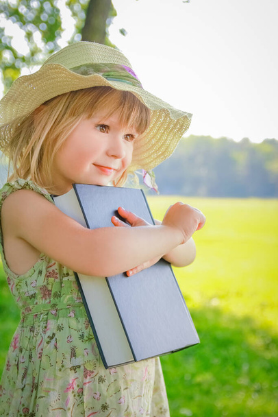 a happy child with a book on the nature of the Bible in the Park - Photo, Image
