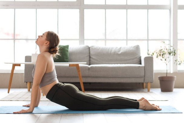 Giovane donna sportiva che fa yoga a casa - Foto, immagini