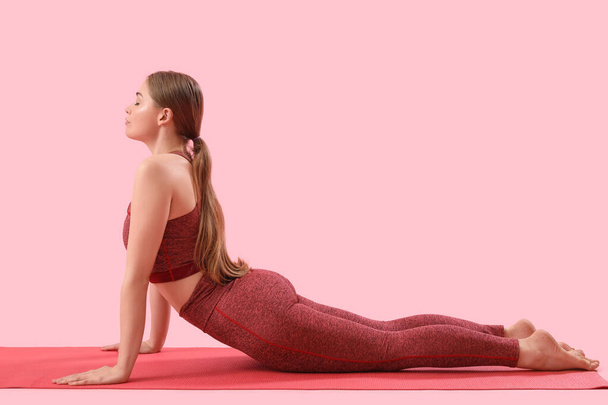 Sportovní mladá žena dělá jógu na růžovém pozadí - Fotografie, Obrázek