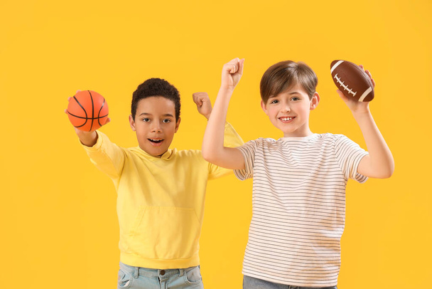 Niños pequeños con pelotas sobre fondo amarillo. Celebración del Día de los Niños - Foto, Imagen