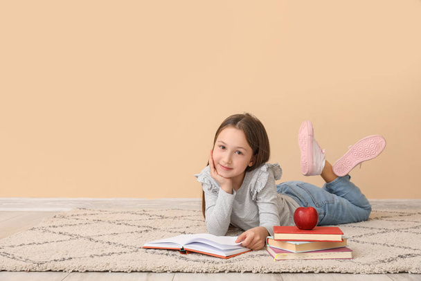 Una niña leyendo un libro cerca de la pared beige. Celebración del Día de los Niños - Foto, imagen