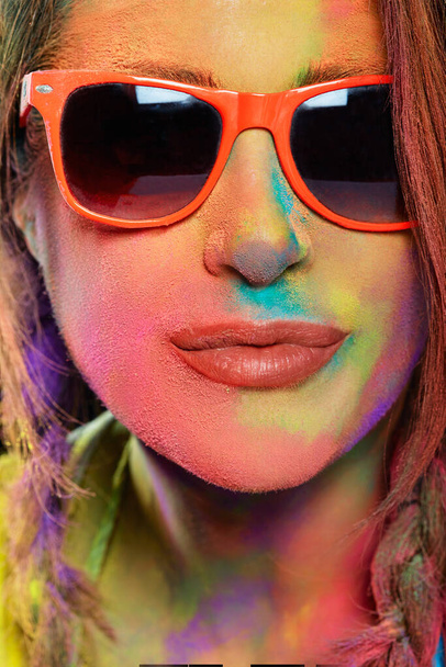 Bella giovane donna con occhiali da sole ricoperti di polvere di Holi color arcobaleno. Ritratto da studio. Formato verticale - Foto, immagini