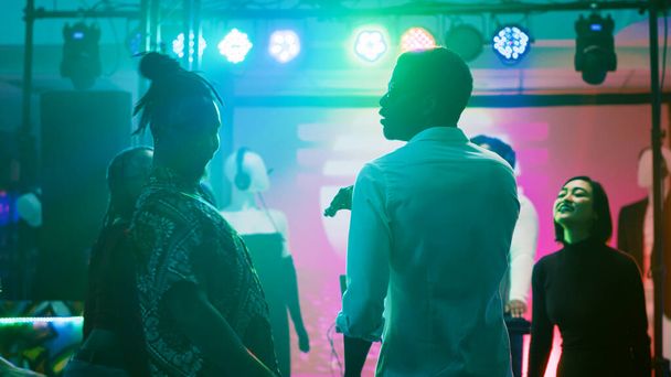 Διαφορετικοί ενήλικες χορεύουν σε ντίσκο πάρτι, funky άνθρωποι αισθάνονται έτοιμοι να αναδείξουν τις χορευτικές τους κινήσεις στην πίστα. Χαρούμενοι νέοι άνδρες και γυναίκες που απολαμβάνουν τη μουσική στη ντισκοτέκ. - Φωτογραφία, εικόνα