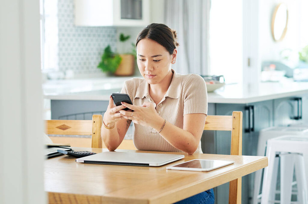 Sending out a quick text while I can. an attractive young woman sitting alone and using her cellphone to work from home - 写真・画像