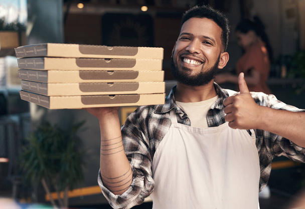 Веве отримав найкращу піцу в місті. гарненький молодий чоловік стоїть біля свого ресторану і тримає купу піци. - Фото, зображення