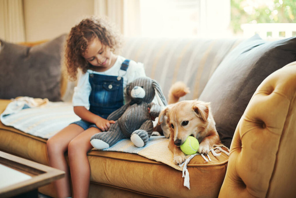 Enjoying home time with my dog. an adorable young girl sitting on the sofa at home and bonding with her dog - Zdjęcie, obraz