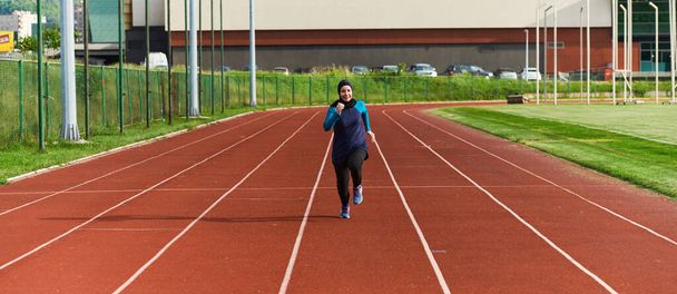 Une femme musulmane dans un burqa sport vêtements musulmans courir sur un parcours de marathon et se préparer pour les prochaines compétitions.  - Photo, image