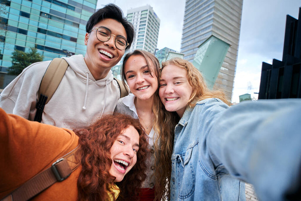 Sonriendo estudiantes universitarios multiétnicos tomando selfie en erasmus Europe. Foto de amigos felices juntos fuera del campus universitario sonriendo. Jóvenes alegres posan y se divierten. - Foto, imagen