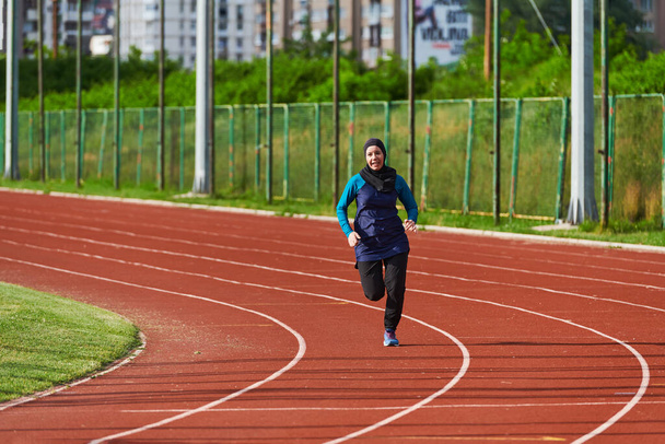 A muslim woman in a burqa sports muslim clothes running on a marathon course and preparing for upcoming competitions.  - 写真・画像