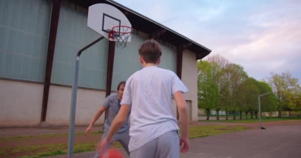 La famiglia trascorre il tempo libero insieme facendo sport e giocando a basket sul campo da basket vicino alla scuola. Rafforzare la salute della famiglia, uno stile di vita sano. Allenamento di basket. - Filmati, video