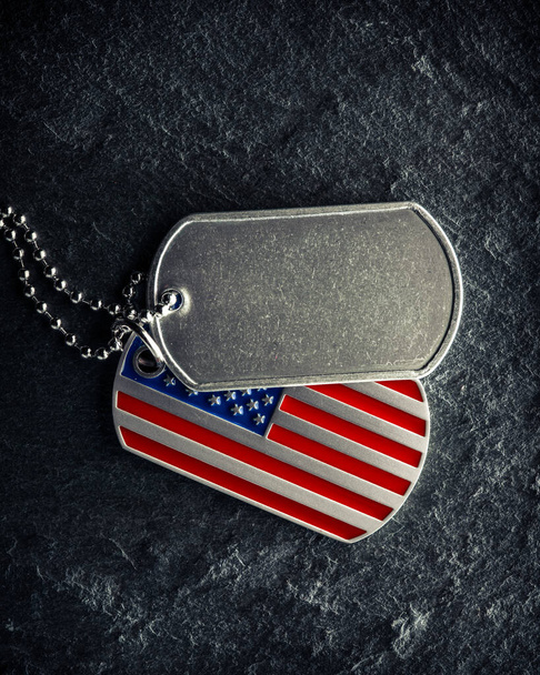 Nieśmiertelniki amerykańskiego żołnierza, szorstkie i noszone z pustym miejscem na tekst, i w kształcie amerykańskiej flagi. Dzień Pamięci dla Weteranów koncepcja Day. - Zdjęcie, obraz