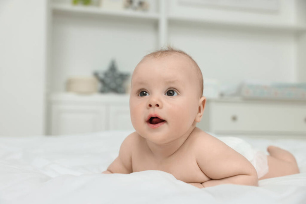 Cute baby lying on white bed at home, space for text - Foto, Imagem