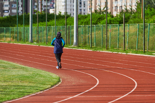 Muzułmanka w muzułmańskim stroju sportowym, biegająca na maratonie i przygotowująca się do nadchodzących zawodów.  - Zdjęcie, obraz