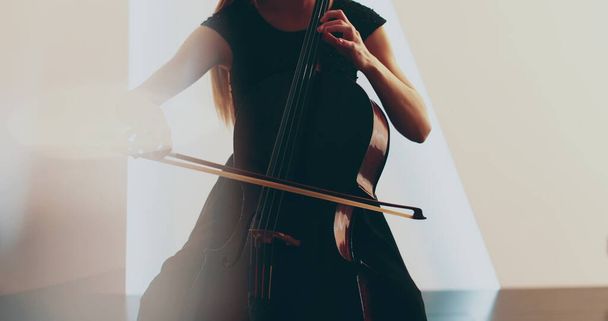 Mujer soltera tocando el violonchelo, primer plano y primer plano medio, arco de violonchelo y cuerdas, transiciones suaves de la cámara de enfoque a fuera de foco, hermosas tomas fílmicas, artísticas. - Foto, imagen