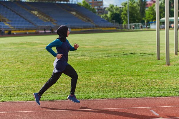 A muslim woman in a burqa sports muslim clothes running on a marathon course and preparing for upcoming competitions.  - Fotó, kép