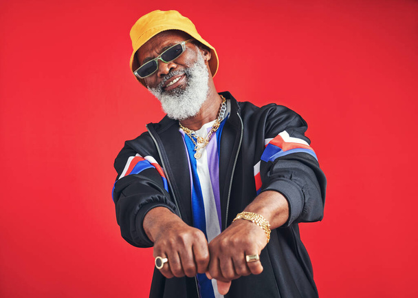 Hes everyones friend. Studio shot of a senior man wearing retro attire while posing against a red background - Photo, Image