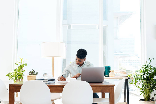 Werk hard tot er succes is. een jonge zakenman die een laptop gebruikt en papierwerk bekijkt in een modern kantoor - Foto, afbeelding