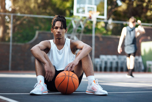 バスケットボールは俺にとって全てだ。バスケットボールコートに座っているスポーティな若者の肖像 - 写真・画像
