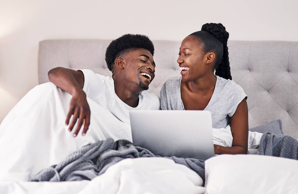 Assustaste-te com o vídeo. um jovem casal usando um laptop enquanto relaxa em sua cama - Foto, Imagem