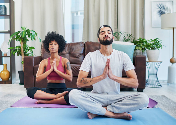 Lo yoga ha migliorato la nostra salute e il nostro rapporto. una giovane coppia che pratica yoga nel loro salotto - Foto, immagini
