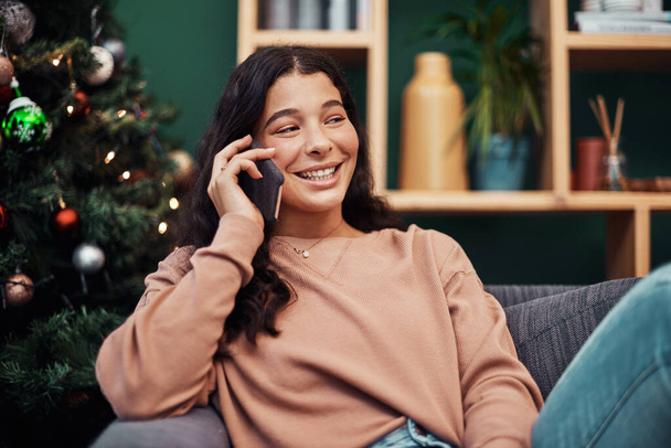Just calling to say, Merry Christmas. a beautiful young woman using a smartphone on the sofa during Christmas at home - Foto, afbeelding