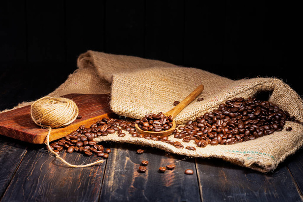 Granos de café frescos colocados sobre una mesa de madera negra, granos de café tostados Espresso Mocha Cappuccino Barista sobre fondo oscuro - Foto, Imagen