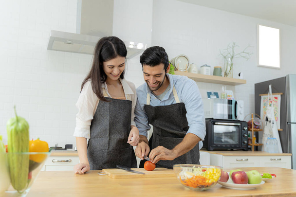 Love of a couple. Young couple having fun while preparing breakfast together in a beautiful morning, cooking together, kitchen relationship, slicing tomatoes together. - Fotografie, Obrázek