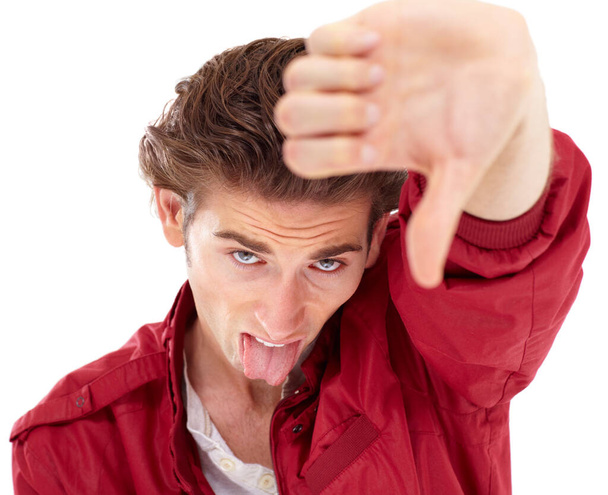 Man in portrait with tongue out, thumbs down and hand gesture for bad opinion isolated on white background. Problem, disagreement and wrong young male person with rejection, fail and negative mindset. - Foto, Bild