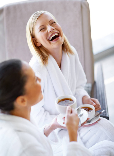 Laughing, talking and friends drinking tea at spa before luxury, beauty and self care treatment. Happy, funny and women bonding, in conversation and enjoying warm beverage together at wellness salon - Foto, Imagem