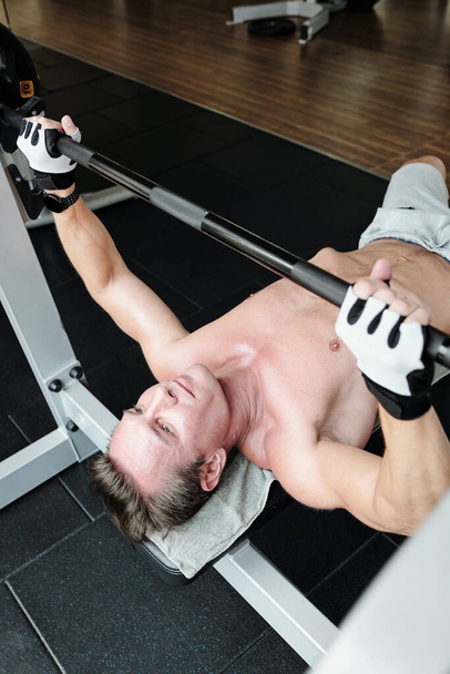 Strong man doing bench press exercise in gym - Fotoğraf, Görsel