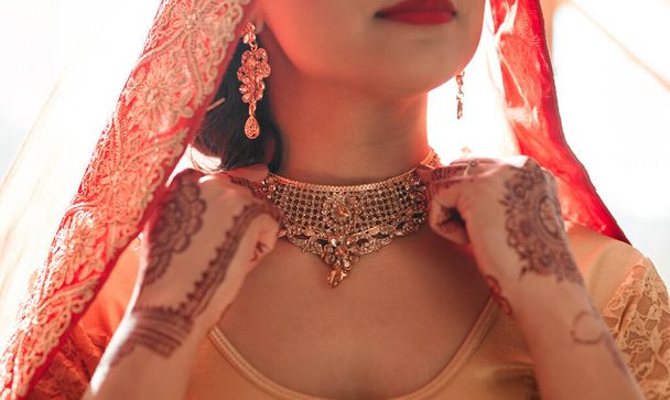 All that glitters is usually gold. a beautiful young woman putting on her necklace in preparation for her wedding - Foto, Imagem