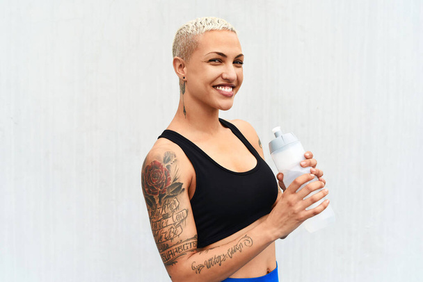 Ik blijf gehydrateerd. Gesneden portret van een aantrekkelijke jonge vrouwelijke atleet drinkwater tegen een grijze achtergrond - Foto, afbeelding