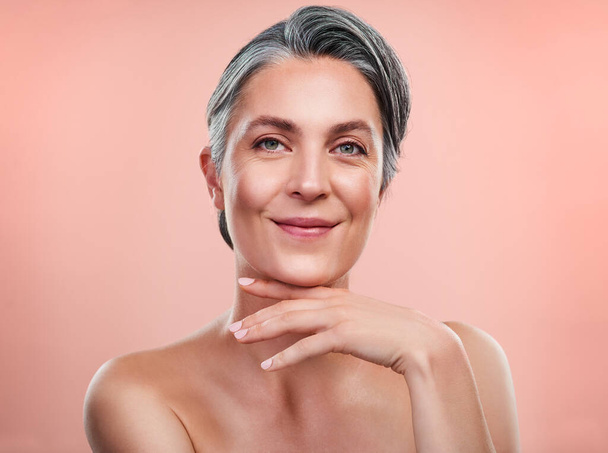 Im sure you want to know my secrets to beautiful skin. Studio portrait of a beautiful mature woman posing against a peach background - Fotoğraf, Görsel