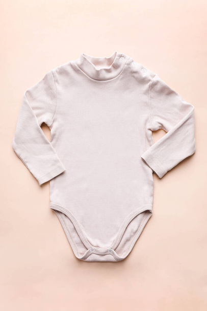 Body de bebé con mangas largas sobre fondo beige. - Foto, Imagen