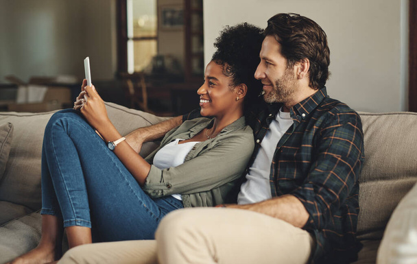 Theres an app for everything nowadays. a happy young couple using a digital tablet together while relaxing on a couch at home - Photo, image