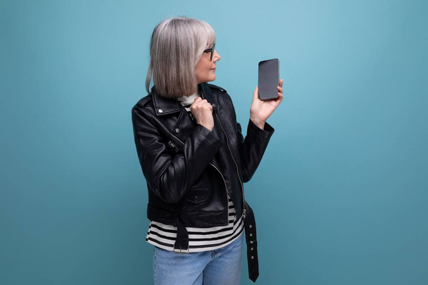 Geschäft mittleren Alters. smart modern 60s moderne alte Frau mit grauen Haaren demonstriert ein Smartphone mit einer Attrappe auf hellem Hintergrund mit Kopierraum. - Foto, Bild