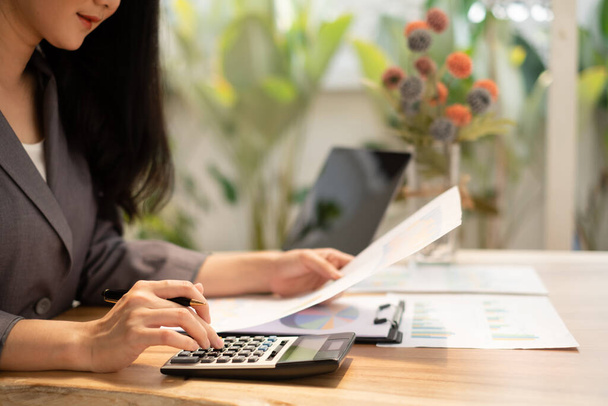 Asiatische Geschäftsfrau sitzen an ihrem Schreibtisch und berechnen Finanzgrafiken, die Ergebnisse ihrer Investitionen zeigen, planen einen erfolgreichen Geschäftsprozess. - Foto, Bild