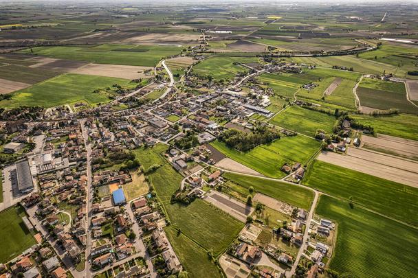 Captivating aerial perspective of a quaint village nestled amidst the lush, green Po Valley farmlands in Italy - Фото, зображення