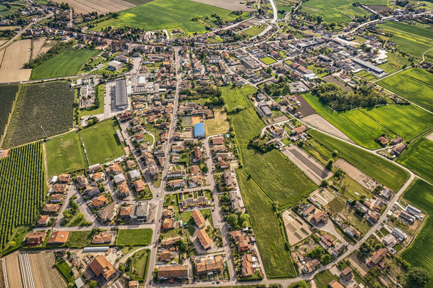 Captivating aerial perspective of a quaint village nestled amidst the lush, green Po Valley farmlands in Italy - Fotoğraf, Görsel