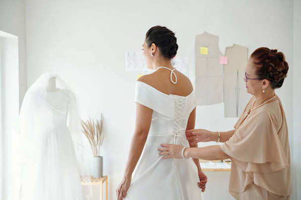 Mãe ajudando filha a apertar espartilho no vestido de casamento - Foto, Imagem