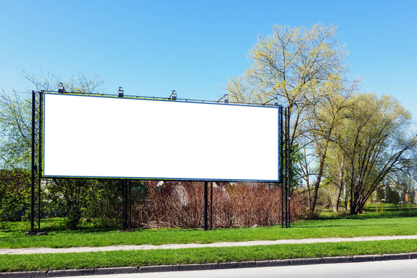 An empty billboard near the trees on a sunny day in spring - Photo, Image