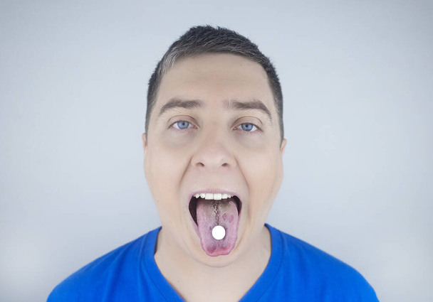 Orale probiotica. Een man stopt een pil met nuttige bacteriën op zijn tong. Dysbacteriose en onbalans van gunstige en schadelijke micro-organismen in de mond. Verhoging van de immuniteit en verbetering van de gezondheid. - Foto, afbeelding