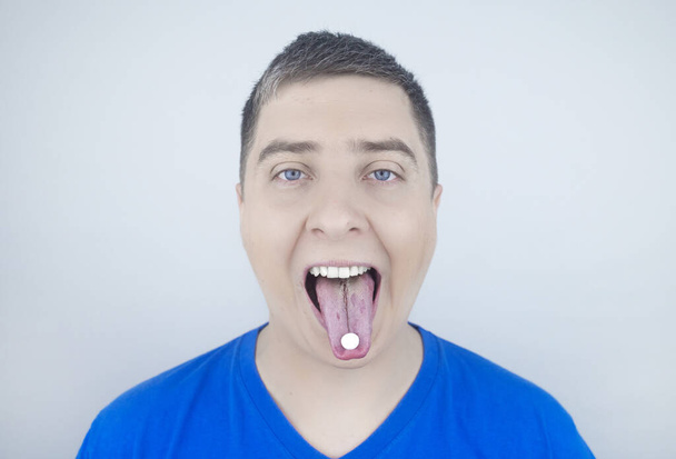 Orale Probiotika. Ein Mann legt sich eine Pille mit nützlichen Bakterien auf die Zunge. Dysbakteriose und Ungleichgewicht zwischen nützlichen und schädlichen Mikroorganismen im Mund. Stärkung der Immunität und Verbesserung der Gesundheit. - Foto, Bild