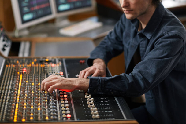 Plan recadré d'un homme du producteur de musique utilisant une station de travail audio numérique dans un studio d'enregistrement professionnel, espace de copie - Photo, image